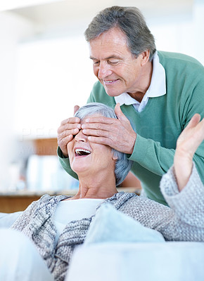 Happy senior man covering his wife\'s eyes to surprise her