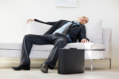 Middle aged business man relaxing in sofa and suitcase on floor