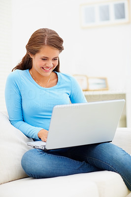 Happy teen girl sitting at home working on a laptop