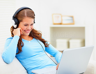 Cute young female listening to music on the laptop