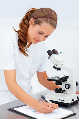 Successful young female researcher working in the laboratory, making notes