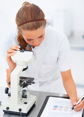Successful female researcher working in the laboratory, making notes