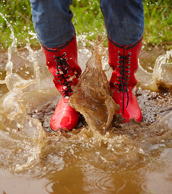 Low section of a female splashing in a muddy puddle