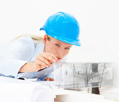 Young female architect looking at a model building isolated on white