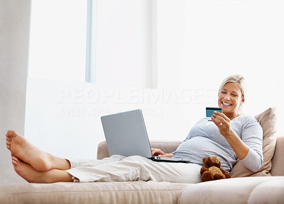 Happy pregnant woman using a credit card to shop online