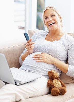 Pregnant female using a credit card and laptop to shop online