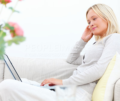 Beautiful young businesswoman sitting on sofa and using laptop