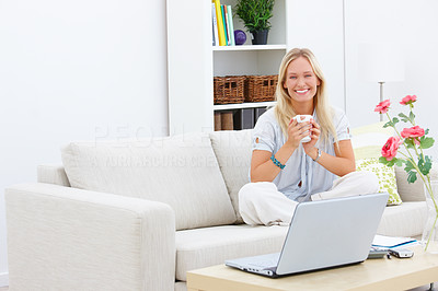 Happy young girl sitting on sofa and drinking coffee