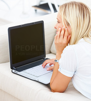 Beautiful young businesswoman lying on sofa and working on computer
