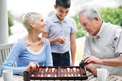 Grandson looking at senior couple play a game of backgammon