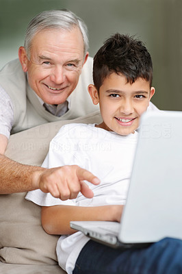 Happy grandfather pointing at the laptop screen to grandson