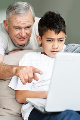Grandfather pointing at the laptop screen to grandson
