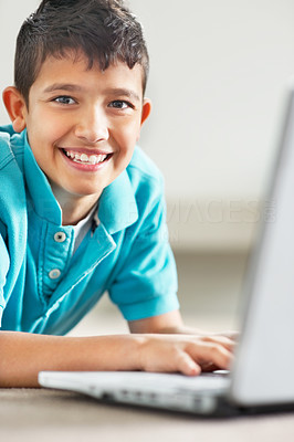 Detail view of a happy cute boy using a laptop on floor