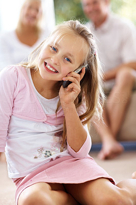 Adorable young girl with mobile while parents in background