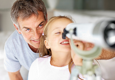 Cute girl looking through telescope with her father