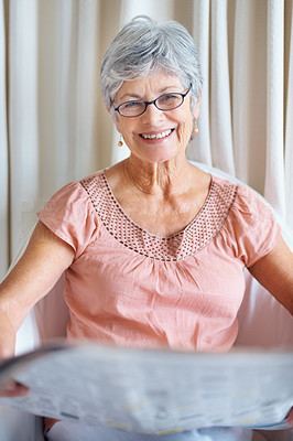 Portrait of a retired happy senior lady reading newspaper