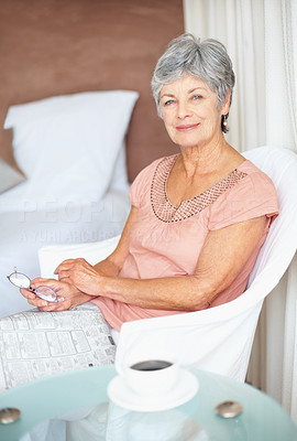 Portrait of a relaxed senior woman sitting with a newspaper