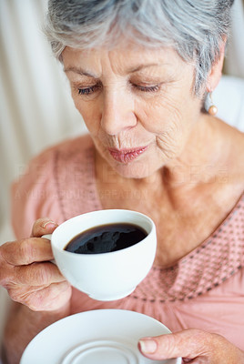 Closeup of a senior lady blowing cool air in her cup of tea