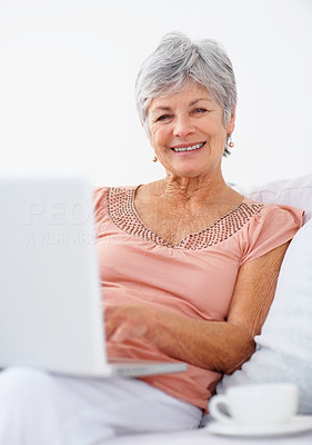 Happy old woman using laptop to browse the internet from home