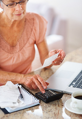 Retired woman budgeting her expenses using a calculator