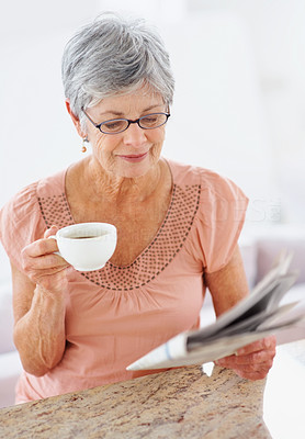 Senior woman reading a newspaper and drinking coffee