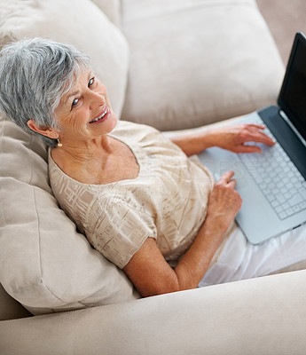 Top view of a senior woman using a laptop on couch