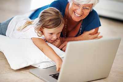 Adorable girl using laptop with grandmother