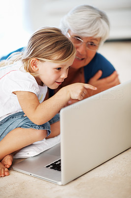 Girl pointing at laptop screen with grandmother