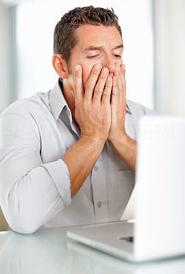 Disappointed middle aged man while looking at laptop screen