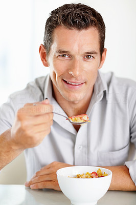 Smiling middle aged man having a bowl of cereal
