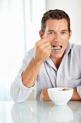 Happy middle aged man eating a bowl of cereal