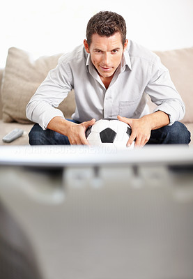 Middle aged man holding football while watching television