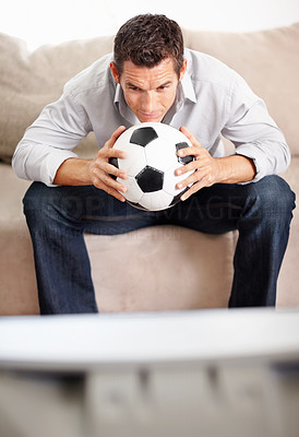 Middle aged man with football while watching live match