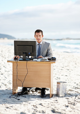 Happy middle aged business man with computer on desk at beach