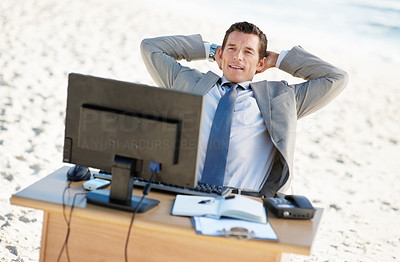 Relaxed middle aged business man at his office desk on a beach