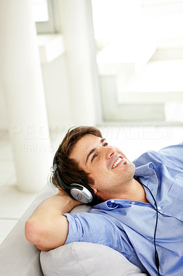 Relaxed yong man listening to music while sitting at home