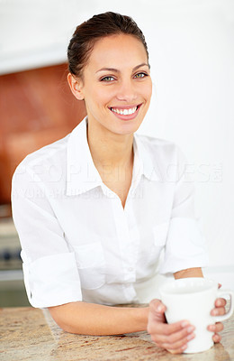 Pretty young woman with a cup of coffee in the kitchen
