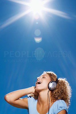 Closeup of happy young lady listening to music outdoors