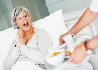 Surprised retired female being served breakfast in bed