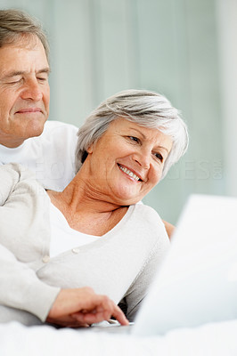 Cute happy senior couple using laptop while in bed