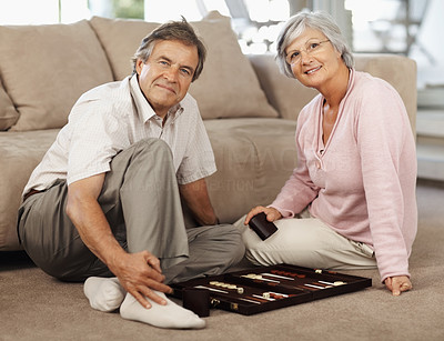 Senior couple playing a game of backgammon on the floor