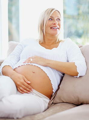 Pretty pregnant woman lost in thought relaxing at home