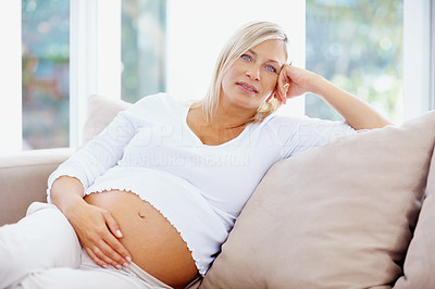 Middle aged pregnant woman holding tummy while at home