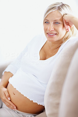 Beautiful mature pregnant woman holding tummy on couch