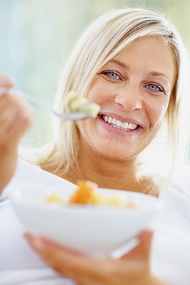 Beautiful mature woman eating a healthy bowl of cut fruits