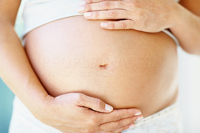 Mid section of a woman holding her pregnant belly