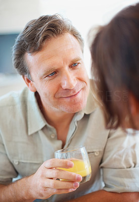 Mature man with a juice glass talking to a woman