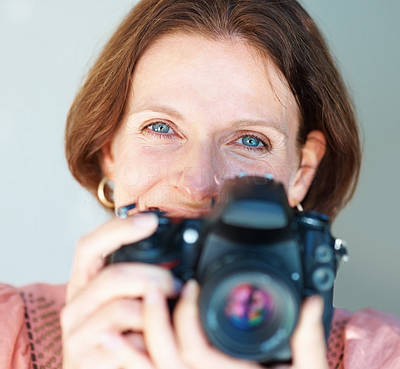 Closeup of a smiling mature woman with a SLR camera