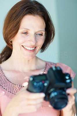 Beautiful middle aged woman looking at her SLR camera