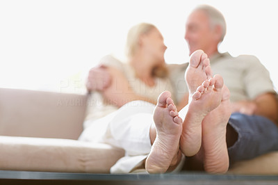Crossed feet of a couple sitting together at home
